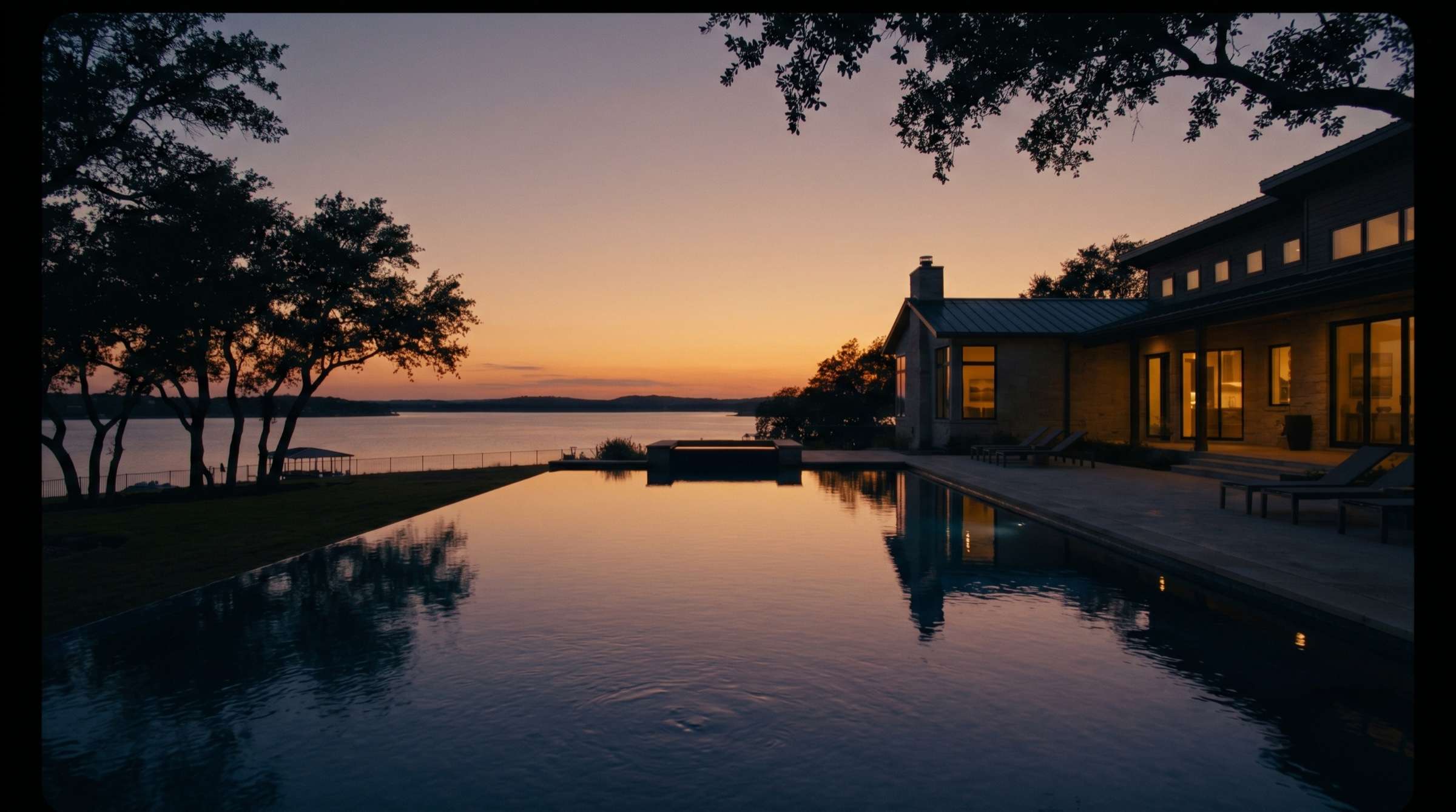 A lakeside estate on Lake Ray Hubbard at dusk, interior lights glowing over an infinity pool