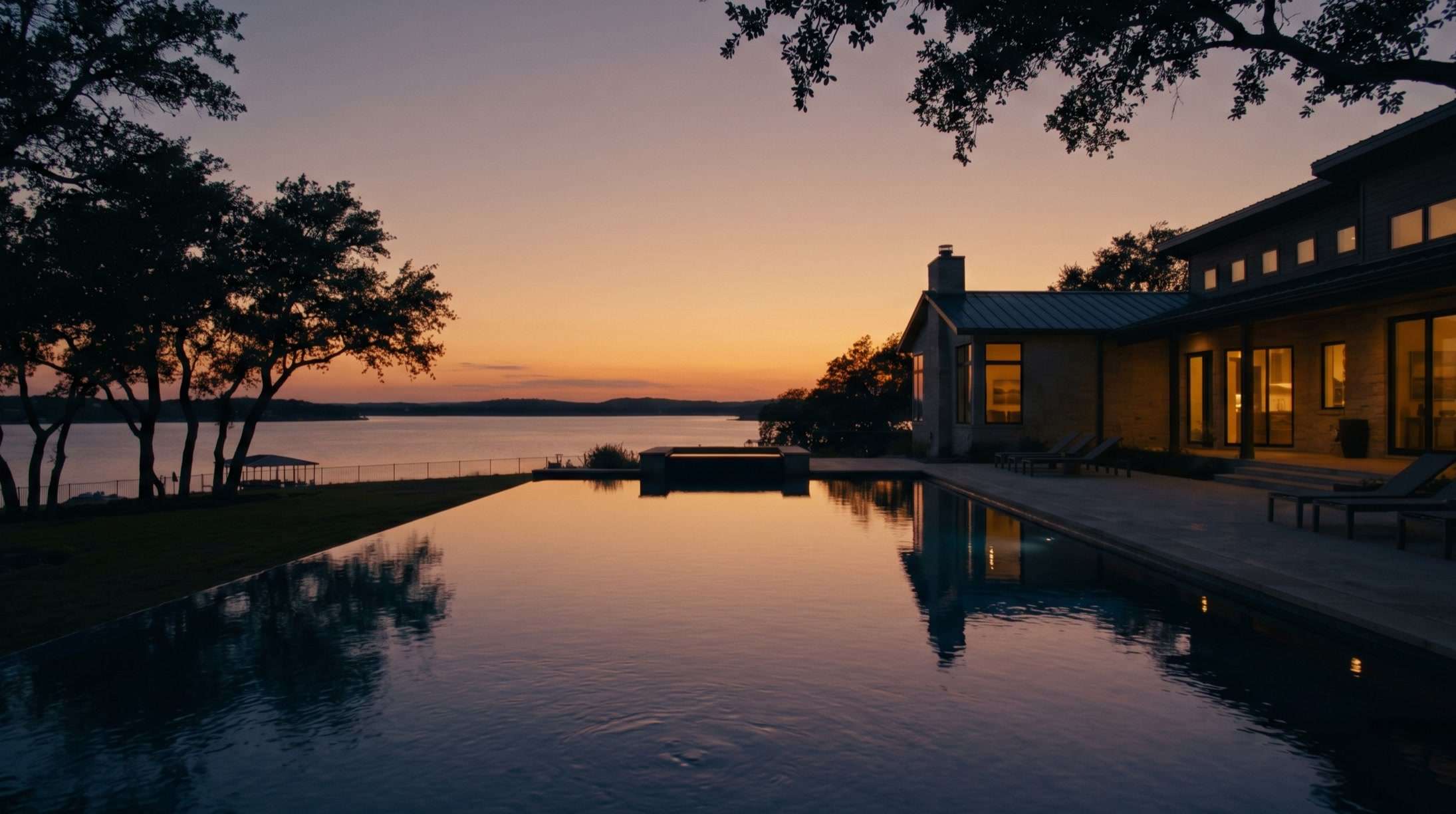 A lakeside estate on Lake Ray Hubbard at dusk, interior lights glowing over an infinity pool